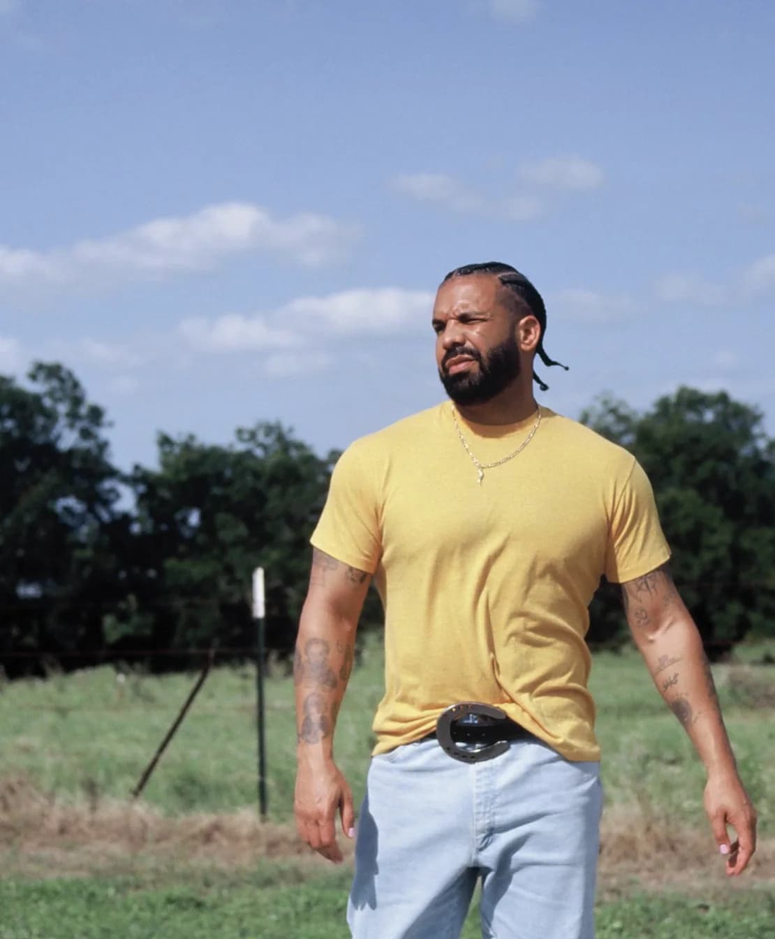 Drake standing outdoors in a yellow shirt